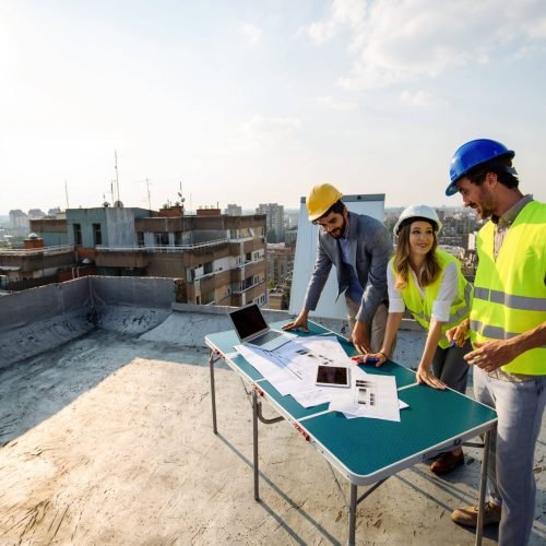 Team of architects and engineers people in group on construciton site check documents