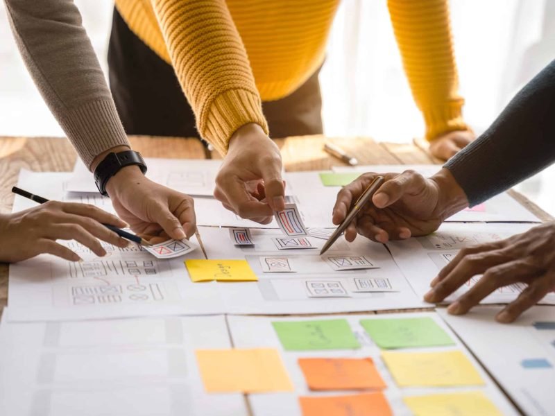 UX developer and ui designer brainstorming about mobile app interface wireframe design with customer breif and color code at office.